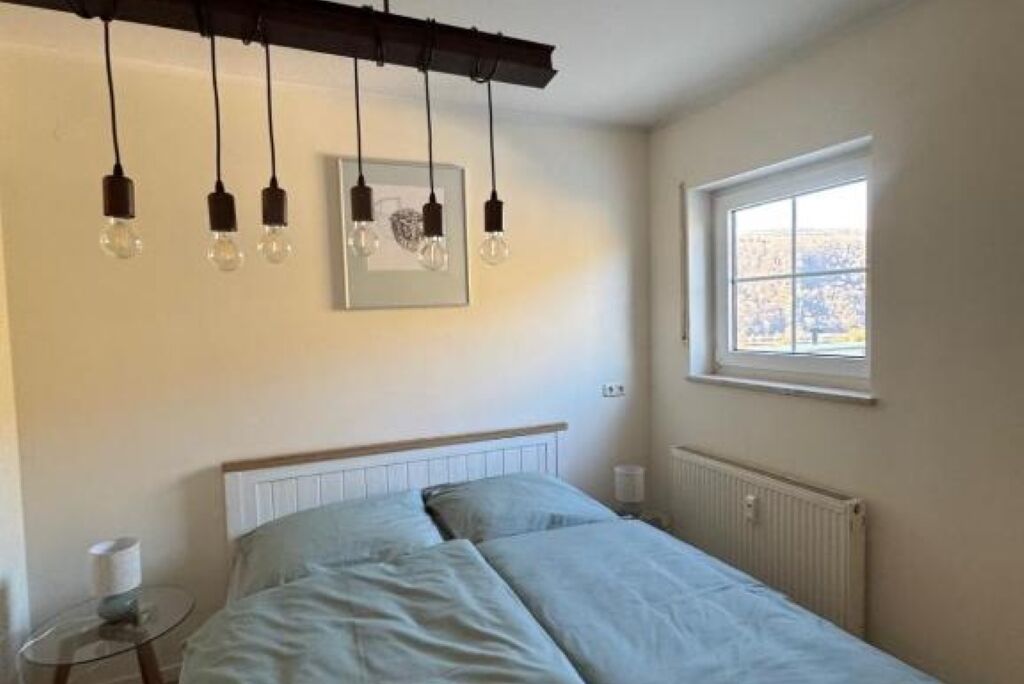 Ein Schlafzimmer mit Bett, Fenster und Pendelleuchten.