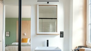 Un baño moderno con un lavamanos blanco, un espejo y un radiador.