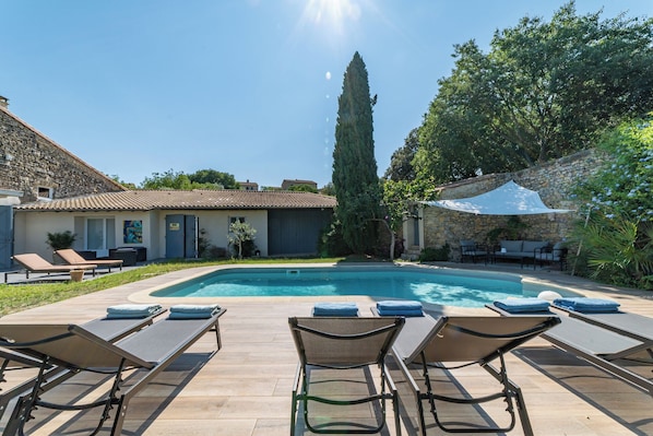 A pool area with lounge chairs and a stone building in the background.