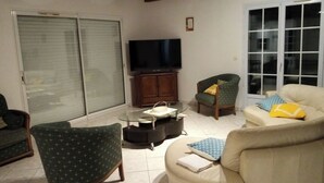 A living room with a TV, a sofa, a chair, and a coffee table.