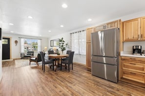 A modern kitchen with wooden cabinets, a stainless steel refrigerator, and a dining area with a round table and chairs.