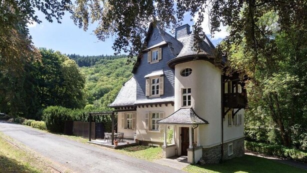 A traditional house with a steeply pitched roof, a small porch, and a well-maintained garden. - Landsitz Kammerburg :Apartment with garden view (Lorch)