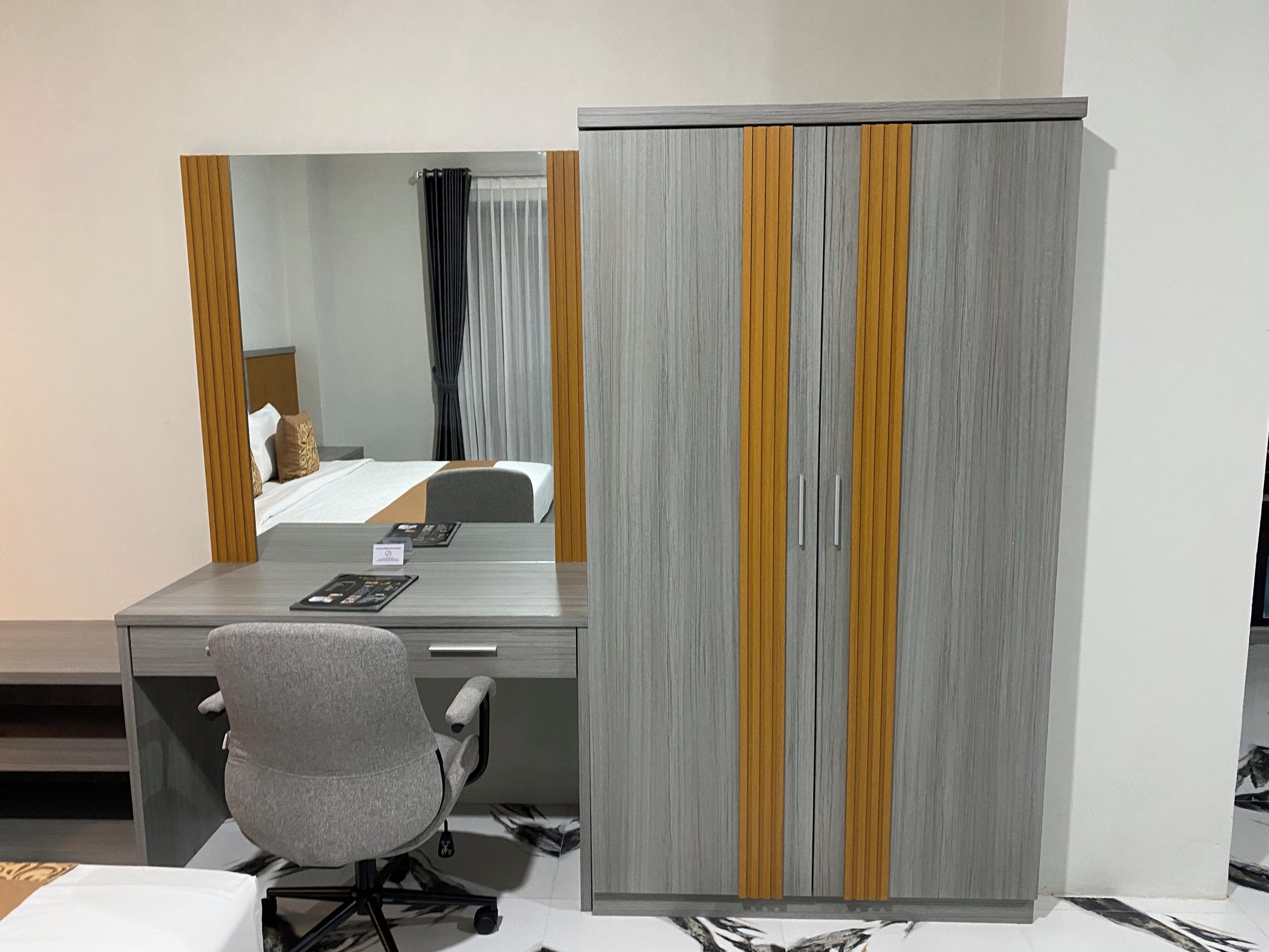 Una habitación de hotel con cama, escritorio, silla, armario y espejo.