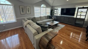 A living room with a sectional sofa, a coffee table, a TV, and a cabinet. -  Spacious 3BR 2BA Apt Near JFK (Jamaica)