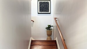 A wooden staircase with white walls and a framed artwork above. -  Spacious 3BR 2BA Apt Near JFK (Jamaica)