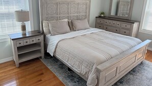 A bedroom with a bed, nightstand, dresser, and a mirror. -  Spacious 3BR 2BA Apt Near JFK (Jamaica)