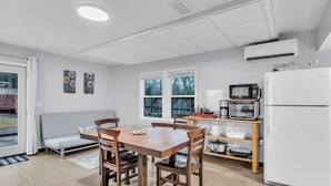 A compact kitchen with a dining table, chairs, a microwave, a refrigerator, and a small window.
