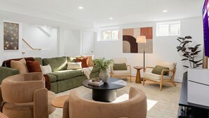 A modern living room with a green sofa, beige armchairs, and a round coffee table. - Modern 3BR • Near Downtown Boston • Walk to T • Minutes to Logan • Free Parking (Boston)