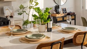 A dining table set with plates, glasses, and a bottle of wine, surrounded by wicker chairs. - Modern 3BR • Near Downtown Boston • Walk to T • Minutes to Logan • Free Parking (Boston)
