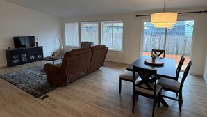 Ein modernes Wohnzimmer mit einer Couch, einem Esstisch und einem Fernseher.