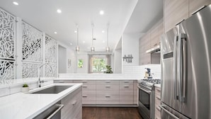 A modern kitchen with a central island, stainless steel appliances, and a decorative white partition. - The Sage Sanctuary: A Sensory Friendly 4BR Retreat in the Heart of Denver (Denver)