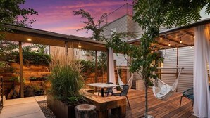 A wooden deck with a table and chairs, a hammock, and a small tree. - The Sage Sanctuary: A Sensory Friendly 4BR Retreat in the Heart of Denver (Denver)