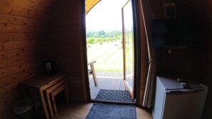 Interior d'una cabana de fusta amb una porta que dona a una terrassa exterior.