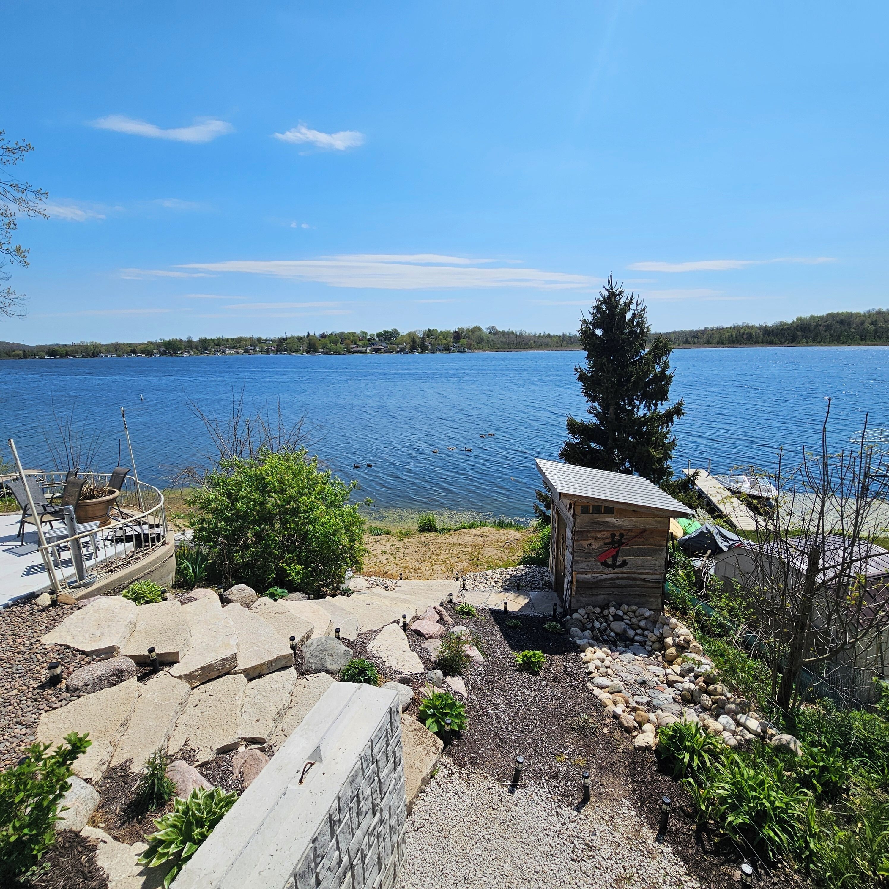 A lakeside property with a dock, a small cabin, and a stone wall.