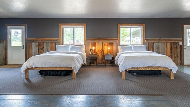 Een kamer met twee bedden, houten hoofdborden en een groot raam.