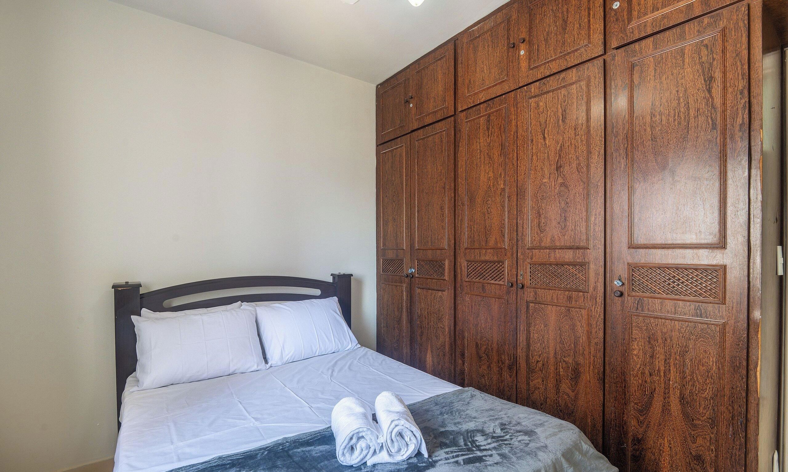Un dormitorio con una cama, un armario de madera y una toalla sobre la cama.