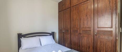 Een slaapkamer met een bed, een houten kledingkast en een handdoek op het bed.