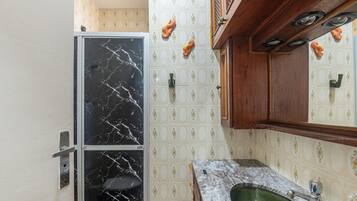 Un baño con lavamanos de mármol, inodoro con puerta de vidrio y azulejos decorativos.