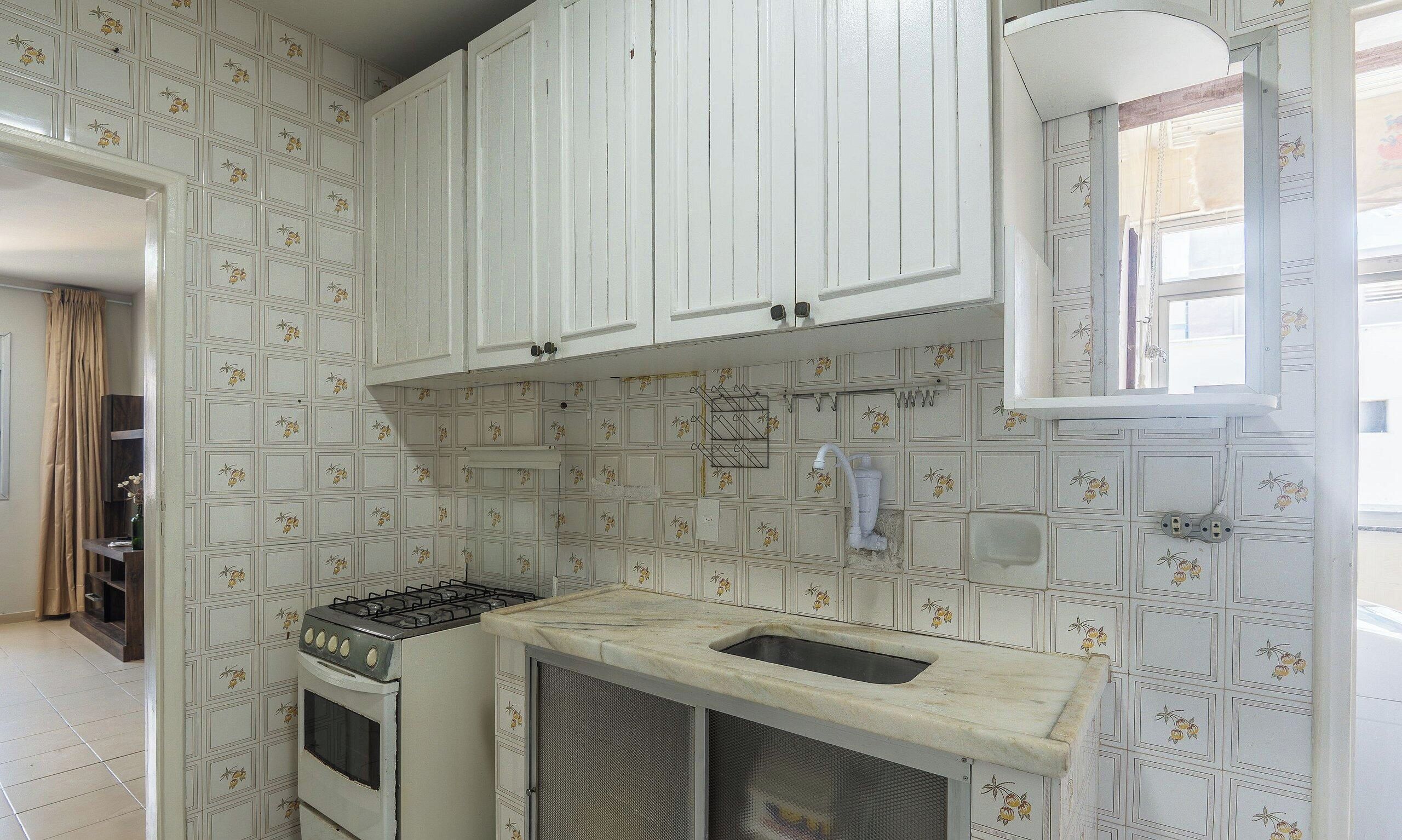 Una cocina con gabinetes blancos, una estufa a gas y un lavamanos.