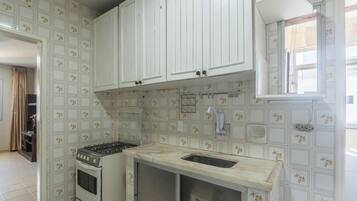 Una cocina con gabinetes blancos, una estufa a gas y un lavamanos.