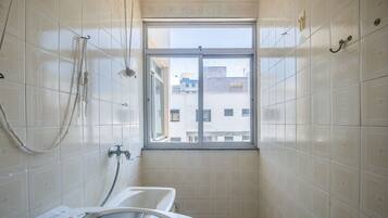 A small bathroom with a window, a bathtub, and a shower.
