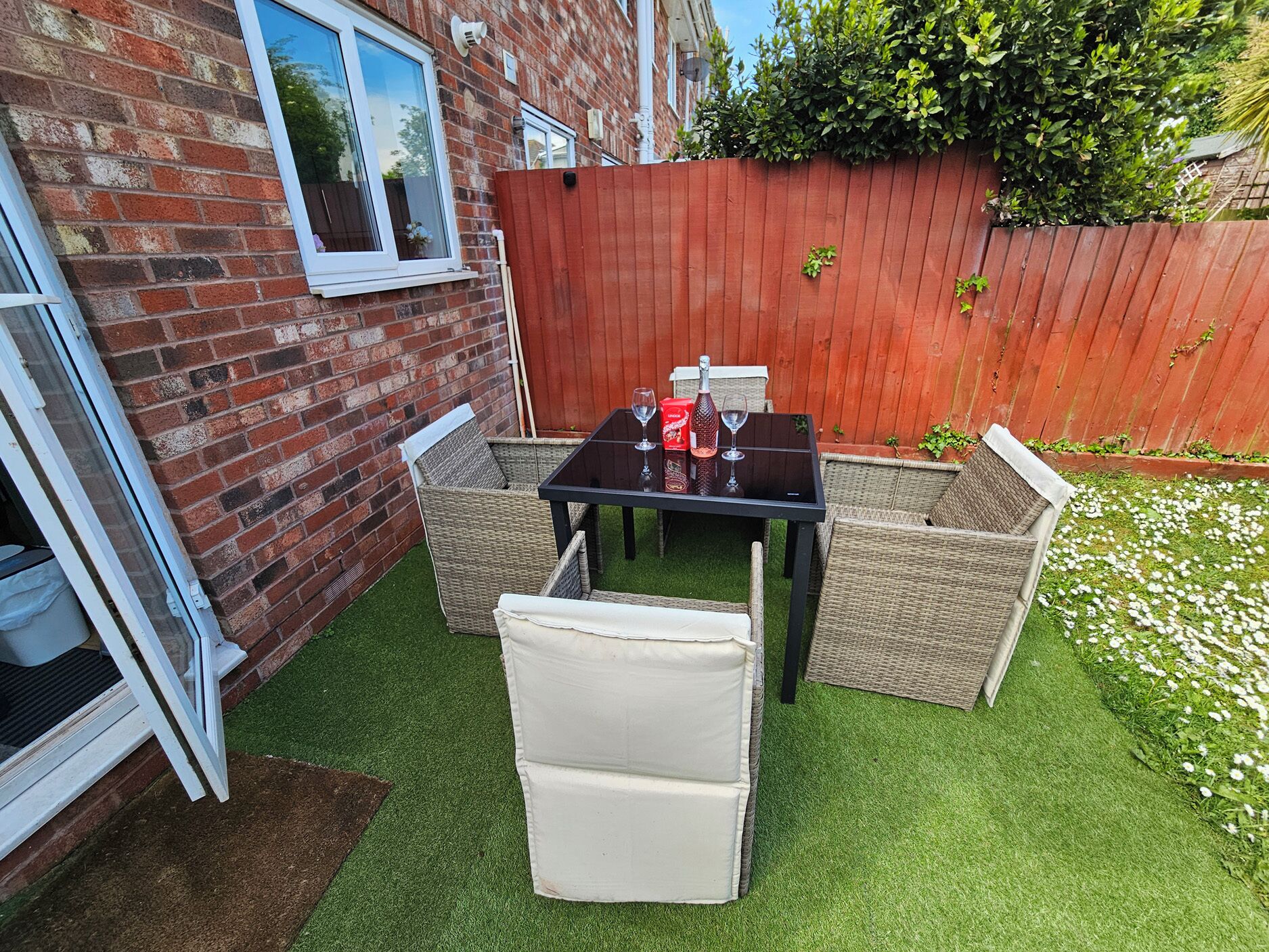 A patio with a table and chairs, a brick wall, and a wooden fence.