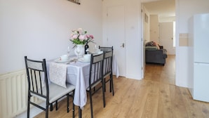 A dining area with a table set for four, chairs, a vase with flowers, and a painting on the wall. - The Cosy View (Paignton)