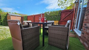 A patio with wicker furniture, a table, and a glass of red wine. - The Cosy View (Paignton)