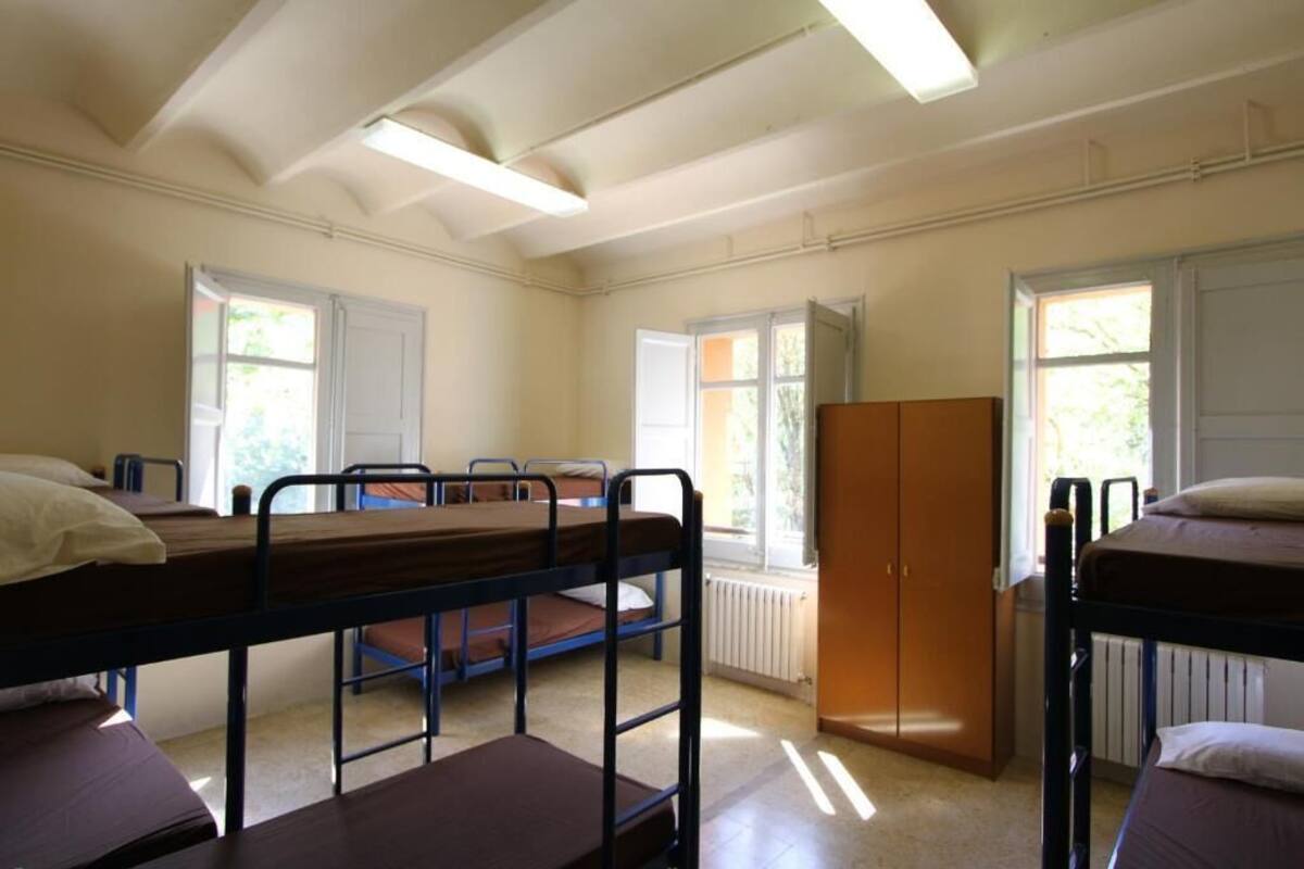 A dormitory room with bunk beds, a wardrobe, and a radiator.