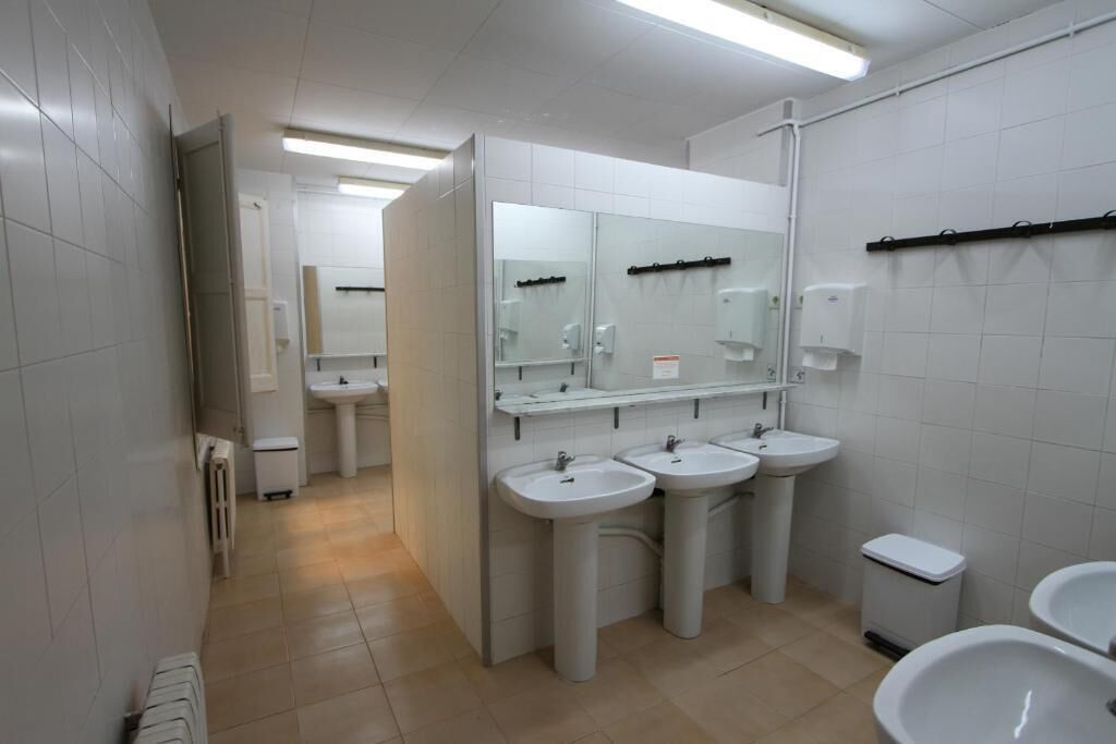 Un baño limpio y moderno con tres lavamanos, un espejo y un inodoro.