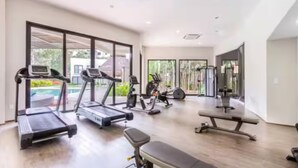 Ein geräumiger Heimfitnessraum mit Laufbändern, Crosstrainern und einer Trainingsbank.