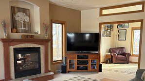 Una sala de estar con chimenea, televisor y sillón de cuero.