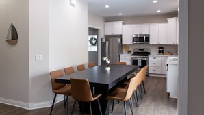 Una cocina moderna con armarios blancos, electrodomésticos de acero inoxidable y una isla central con asientos.
