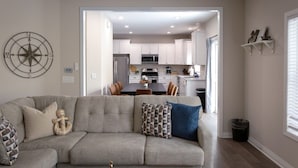 Una sala de estar con un sofá, una mesa de comedor y una cocina al fondo.