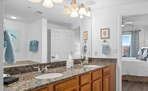 A bathroom with two sinks, a mirror, and a vanity with wooden cabinets. - Entire rental unit in Gulfport, Mississippi (Gulfport)