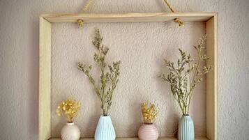 A wooden shelf with four vases containing dried flowers against a textured wall.