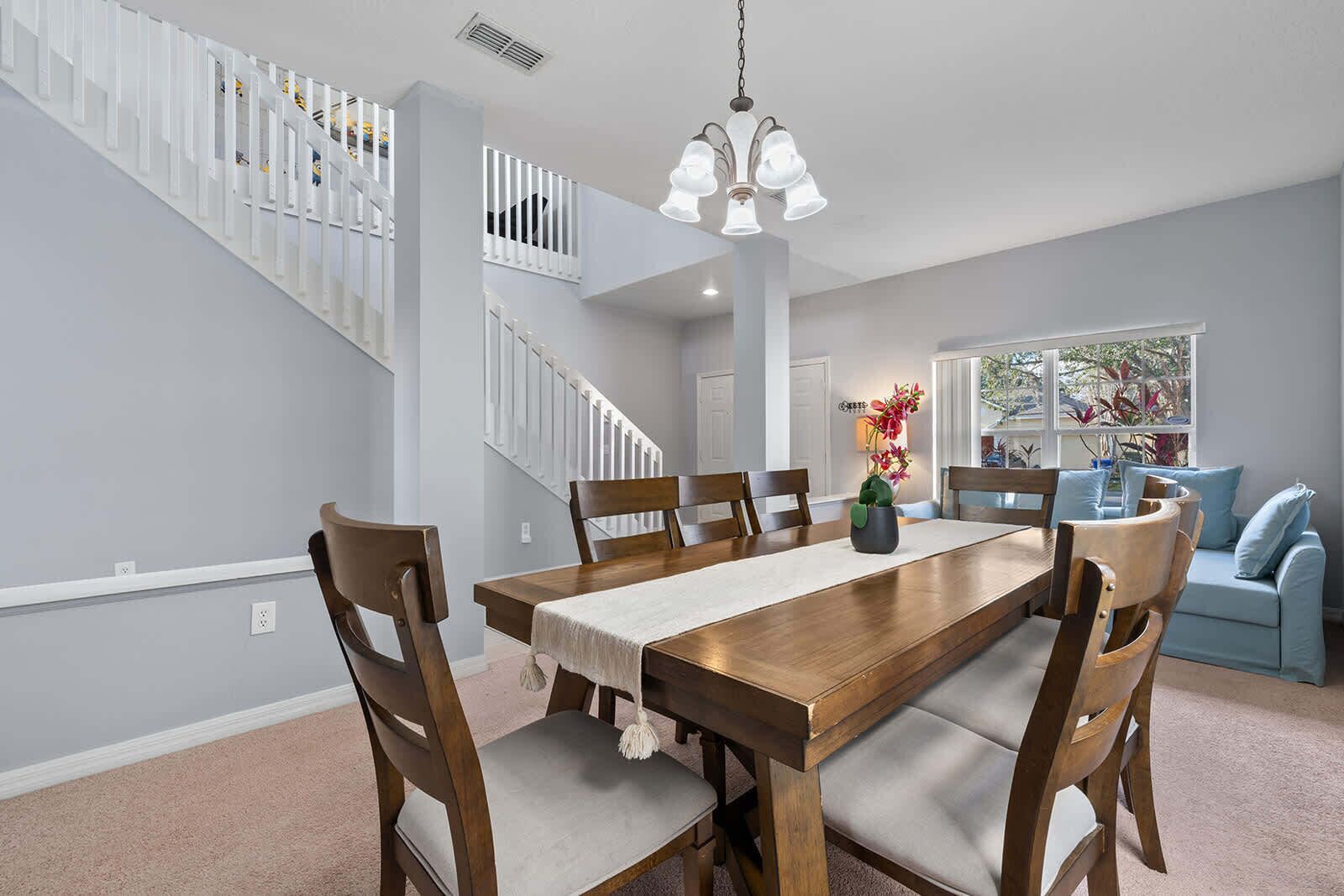 A dining area with a wooden table, chairs, and a chandelier.
