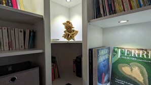 A library with bookshelves, a hanging sculpture, and two books titled 'Volcans des Hommes' and 'La Terre vue du ciel'. - 2-star house - Jardin Clos - Beach, forest and shops on foot (Saint-Hilaire-de-Riez)