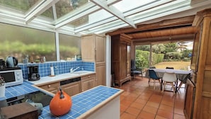 A kitchen with a blue tiled backsplash, wooden cabinets, and a large orange pumpkin on the counter. - 2-star house - Jardin Clos - Beach, forest and shops on foot (Saint-Hilaire-de-Riez)