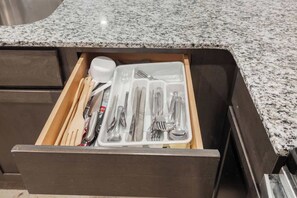A drawer with a set of utensils and a spoon.