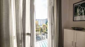 Ein Zimmer mit Blick auf einen Balkon, einem weißen Schrank und einem gerahmten, abstrakten Kunstwerk an der Wand.
