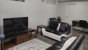 A living room with a flat-screen TV, a sofa, a coffee table, and a painting on the wall. - Unwind in this serene environment with close proximity to the airport. (Calgary)