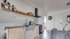 Een moderne keuken met houten kastjes, een inbouwoven en een aanrecht met diverse keukenspullen.