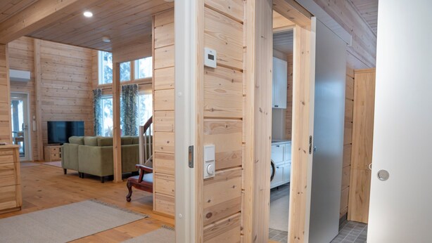 A wooden interior with a sofa, television, and a wooden door. - Villa Siltasaari (Sotkamo)