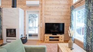 A cozy living room with a fireplace, television, and wooden furniture. - Villa Siltasaari (Sotkamo)