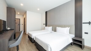 Ein modernes Hotelzimmer mit zwei Betten, einem Schreibtisch und einem Stuhl.