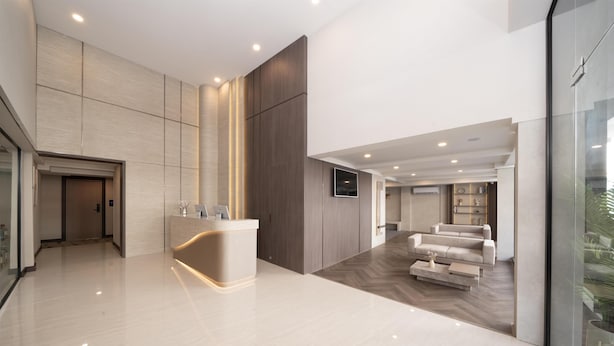 Eine moderne Hotelhalle mit einer Rezeption, einer Sitzecke und einer großen Glaswand.