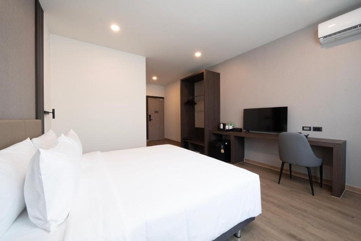 A hotel room with a bed, a desk, a TV, and a wardrobe.