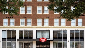 En byggnad med en fasad av tegel, stora fönster och en skylt med texten ”Aiden by BEST WESTERN”.