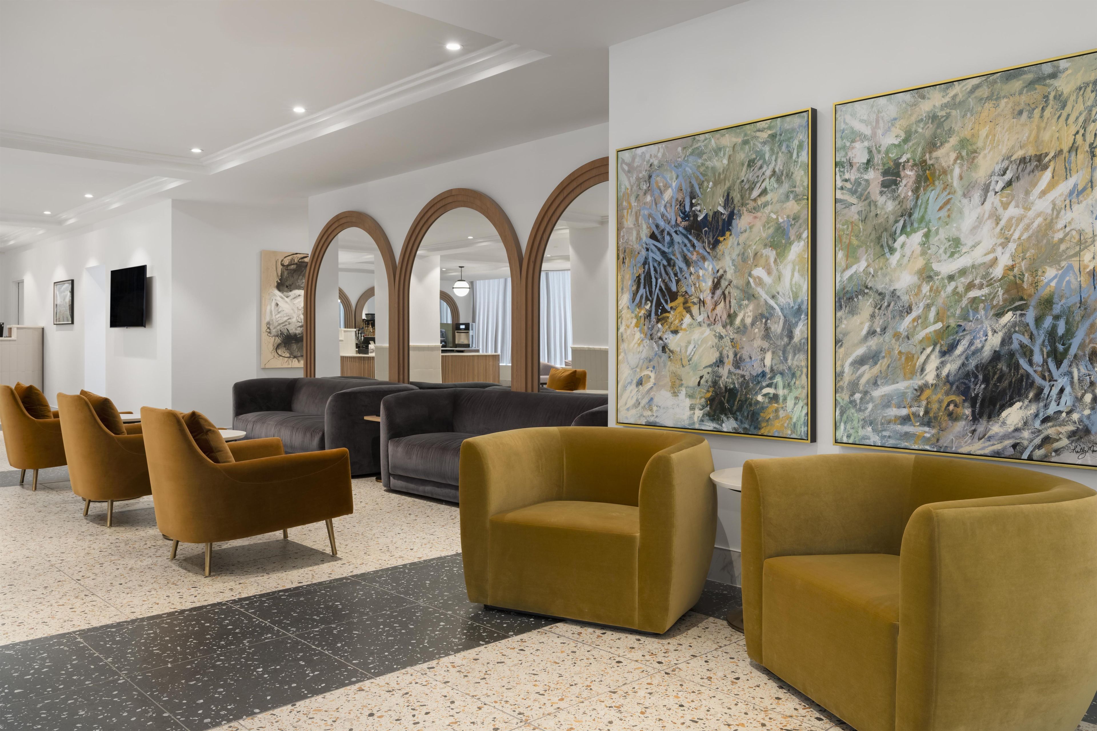 A modern lobby with seating, artwork, and a kitchen area in the background.